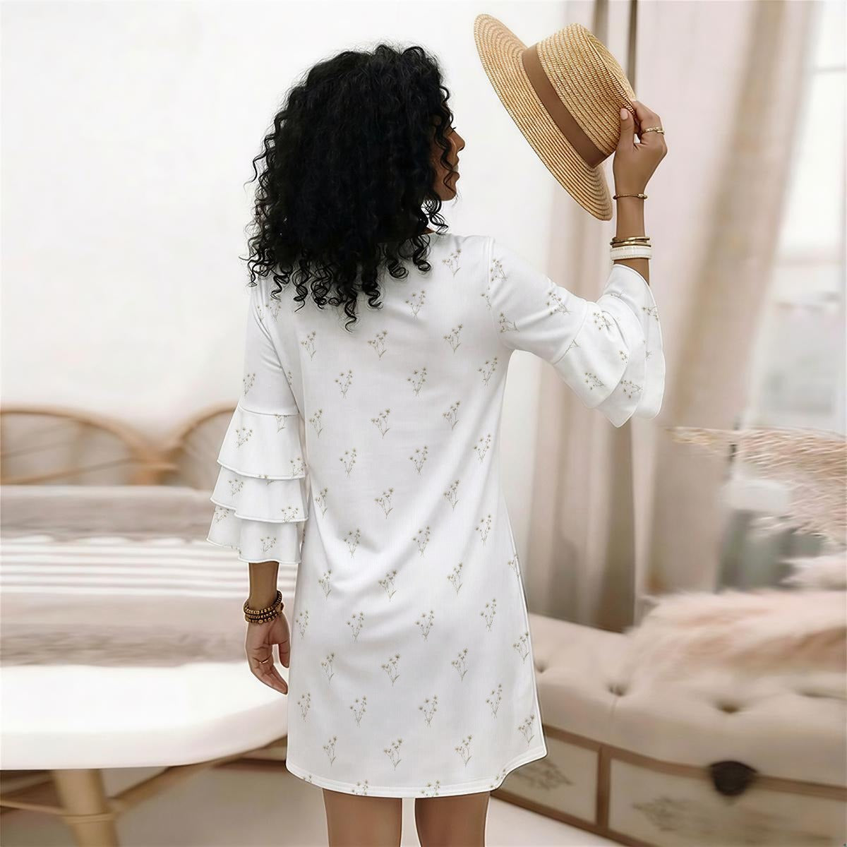 Woman in a white dress holding a straw hat in a room with neutral decor.