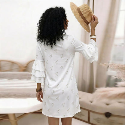 Woman in a white dress holding a straw hat in a room with neutral decor.